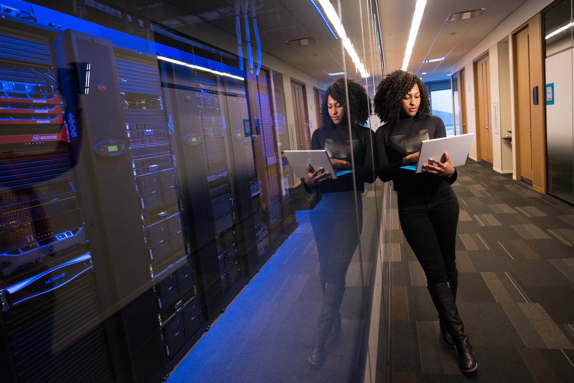 Woman with a tablet leaning against a server room